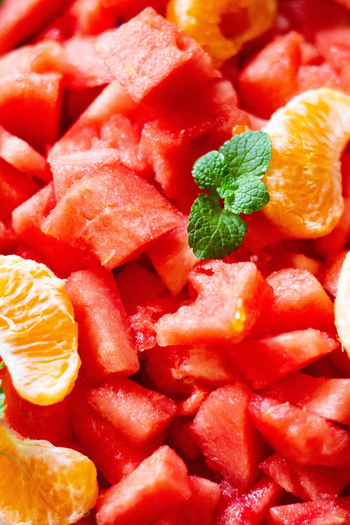 freshly cubed watermelon with a sprig of fresh mint and orange segments