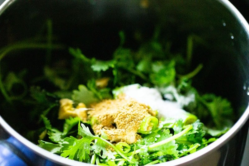 Cumin powder and salt poured on top of chopped leaves in blender.