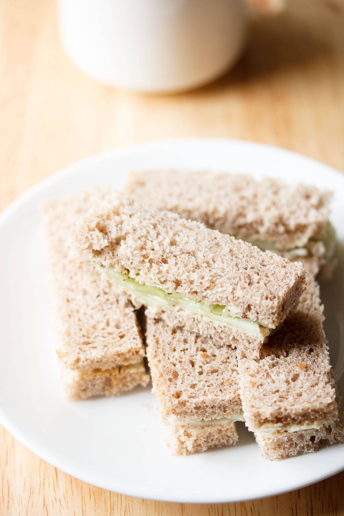 close up shot of cucumber sandwiches on a white plate.