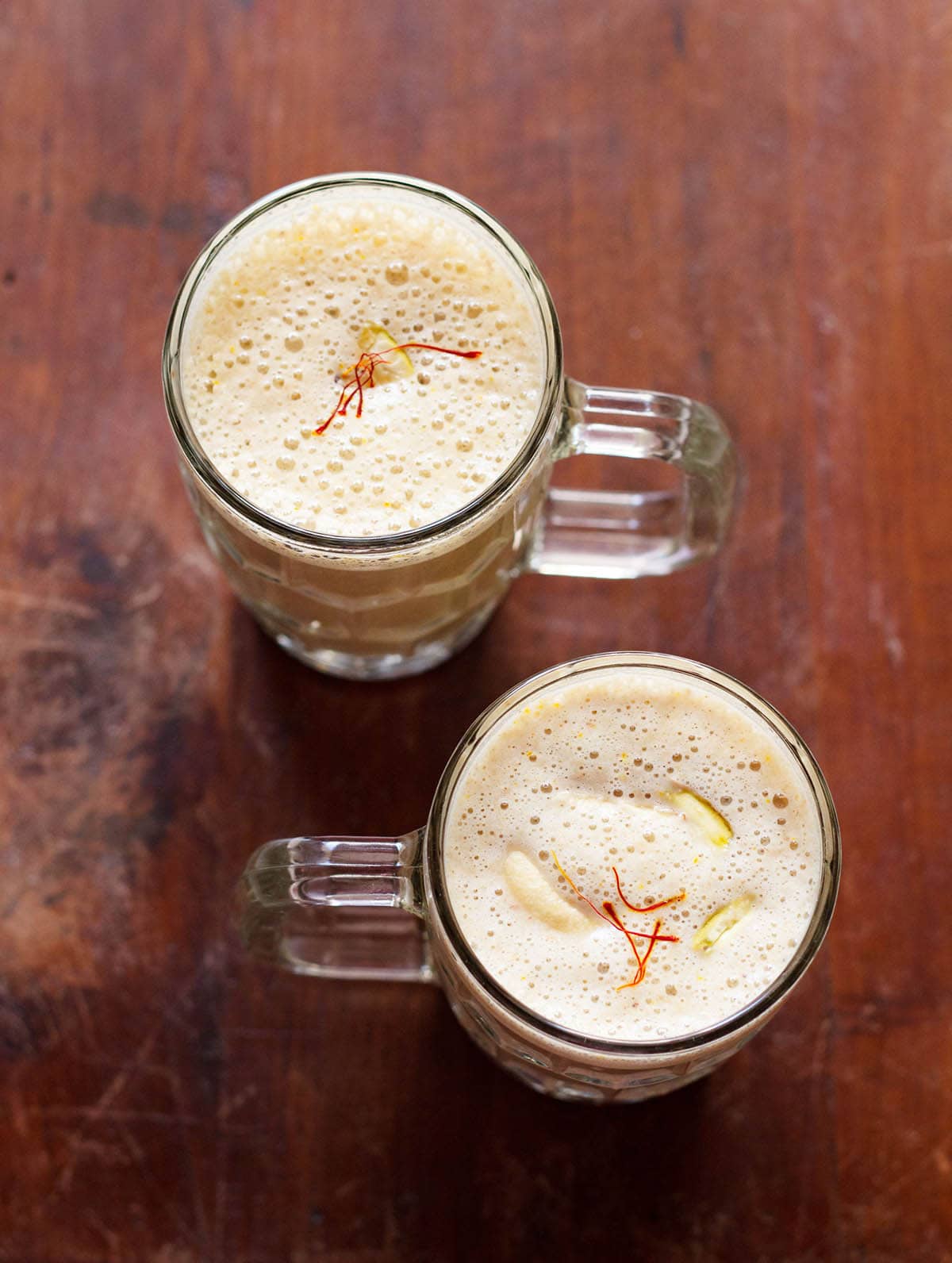dry fruits milkshake in two glasses on a brown wooden board