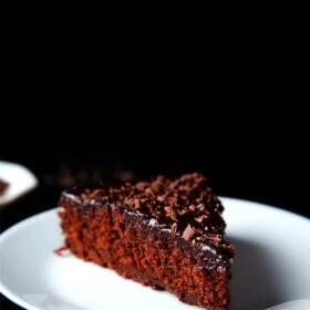 A triangular wedge of eggless chocolate cake on a white plate