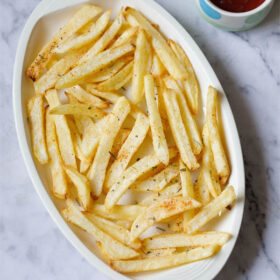 overhead shot of a bowlful of homemade seasoned french fries with dipping sauces