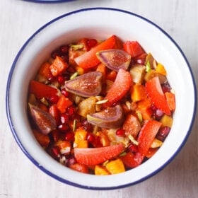 overhead shot of tropical fruit salad in a white bowl with a blue rim