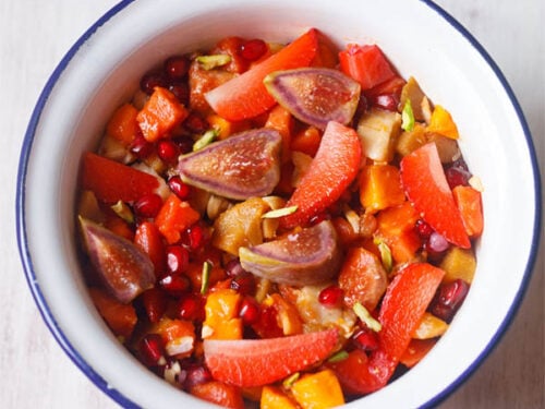 overhead shot of tropical fruit salad in a white bowl with a blue rim