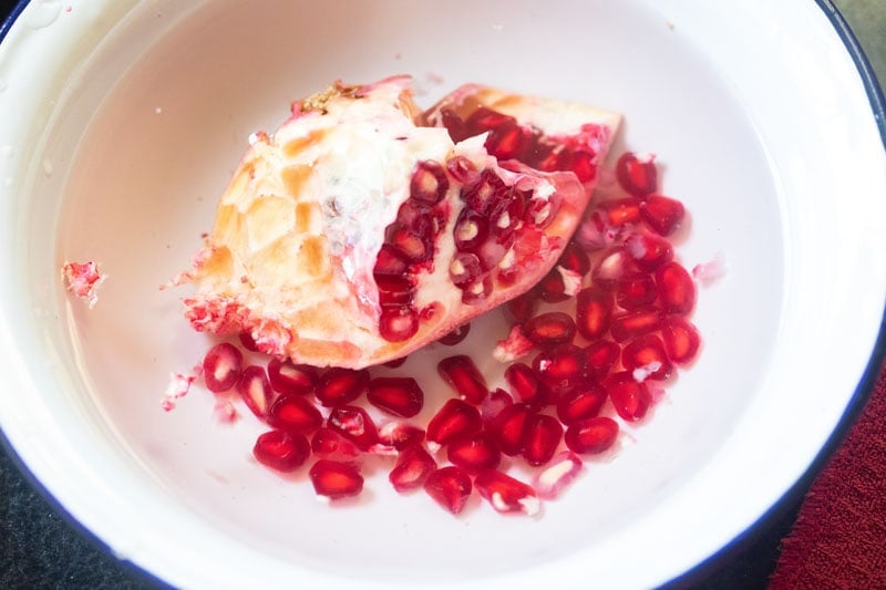 piece of a pomegranate fruit submerged in water to remove arils