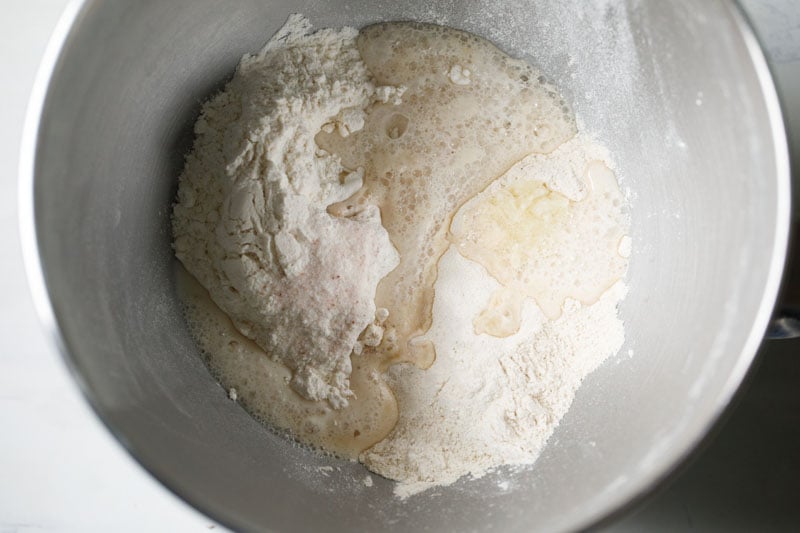 frothy yeast mixture in the bowl with the flour, garlic, oil etc