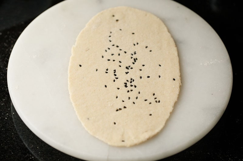 dough rolled to an oblong shape on a white round marble board