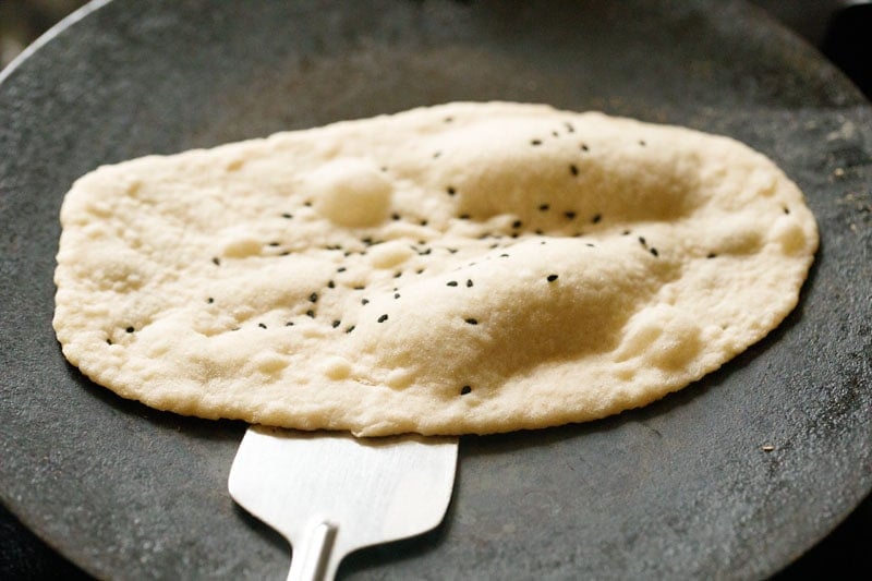 garlic naan being removed with a steel spatula