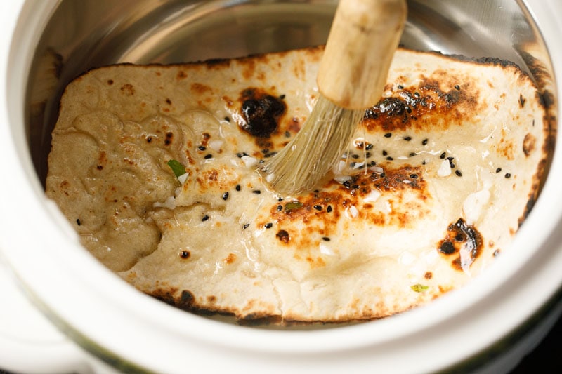 garlic naan in a container box being brushed with garlic and herb butter