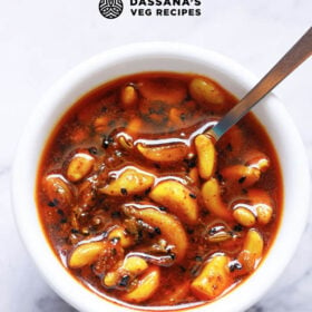 overhead shot of Indian garlic pickle recipe in a white bowl with a sliver spoon with text layovers