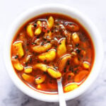 overhead shot of Indian garlic pickle recipe in a white bowl with a sliver spoon