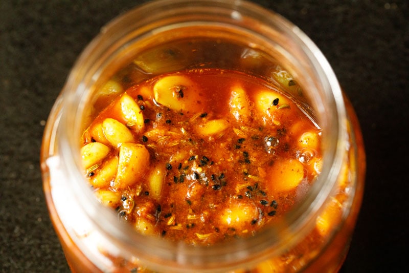 garlic pickle or lahsun ka achaar added to clean glass jar for pickling