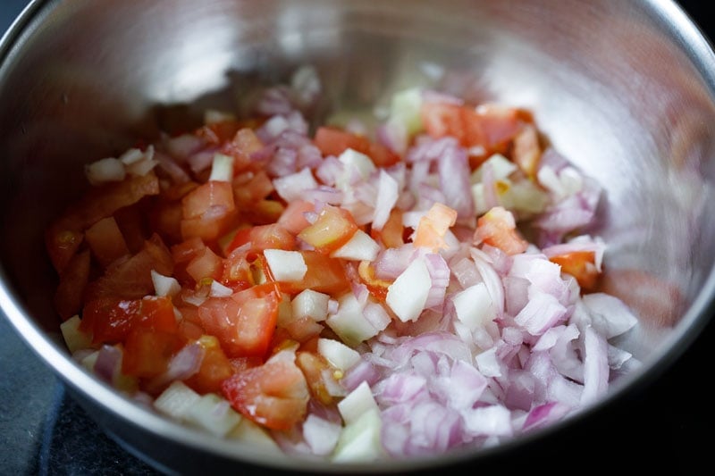 tomatoes, cucumbers and onions in a steel mixing bowl