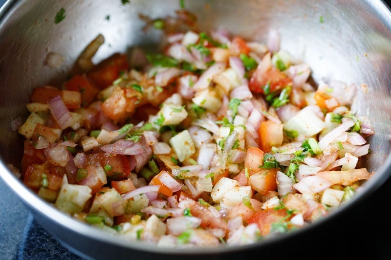 completed kachumber salad in a steel mixing bowl after being tossed together