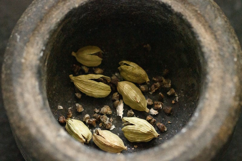 crushed cardamom pods in a stone mortar for sweet lassi