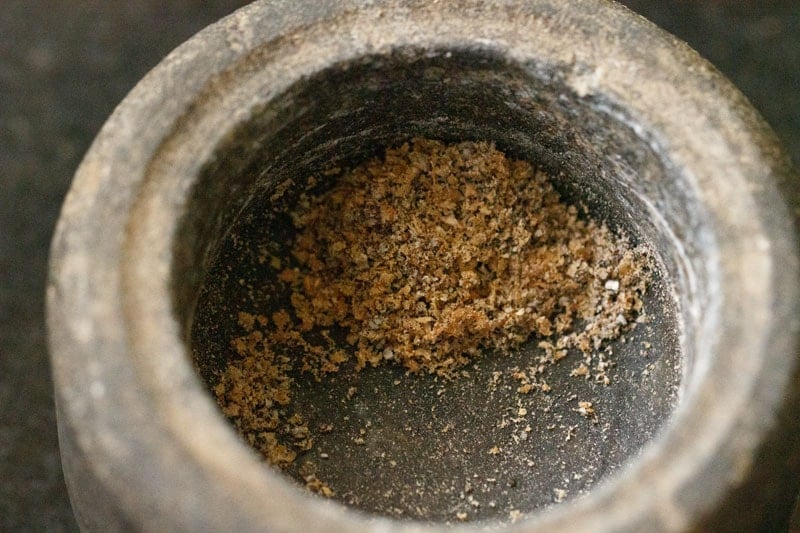 crushed cardamom seeds in stone mortar