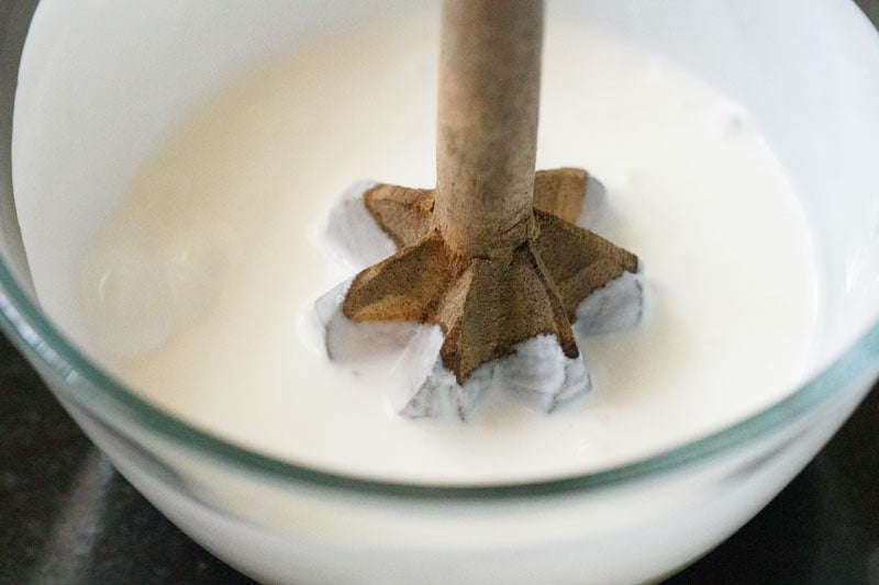 curd being blended with a wooden hand blender