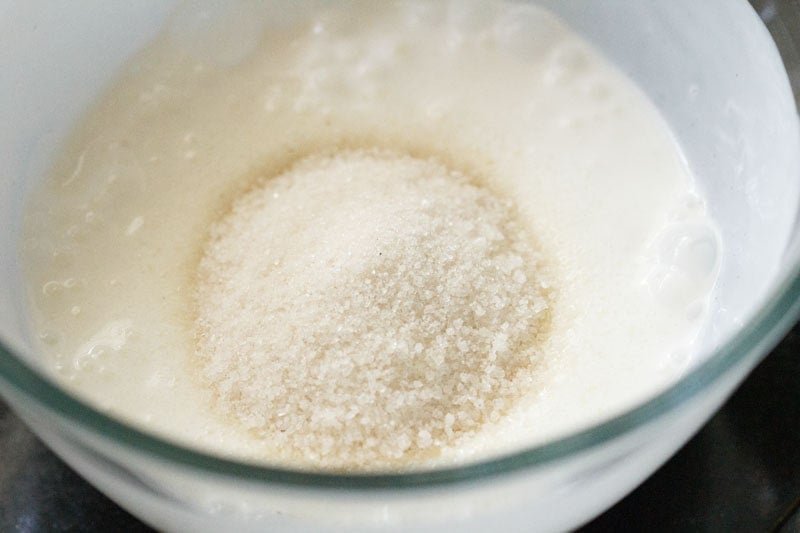 mound of sugar on the whisked curd in the bowl