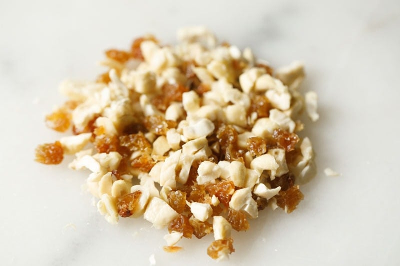 finely chopped cashews and raisins on a white marble board