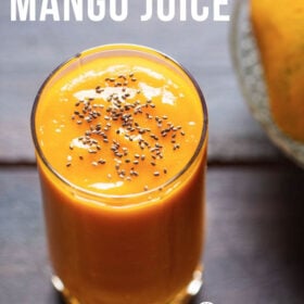 top shot shot of mango juice in a glass topped with chia seeds on a wooden table with a side of mangoes on a glass bowl with a text layover