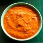 onion chutney in a light green bowl on a dark green board.