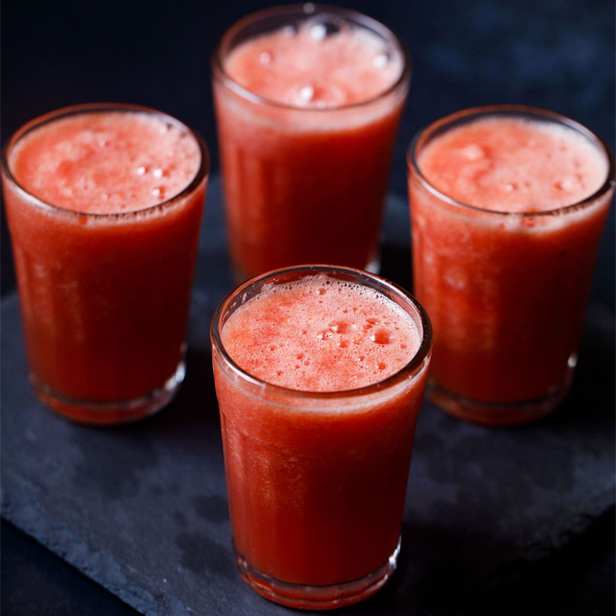 four glasses of watermelon juice arranged in a diamond pattern