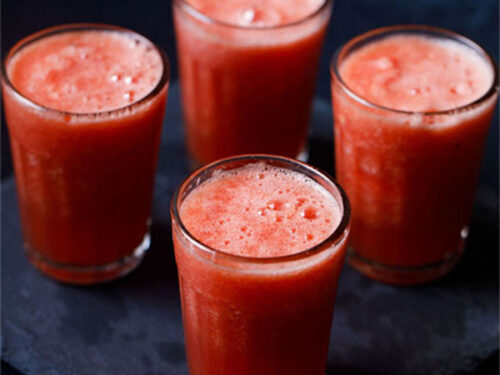 watermelon juice in four glasses or a dark blue table