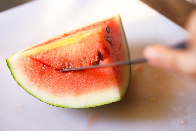 knife sliding under seed line of watermelon on second side
