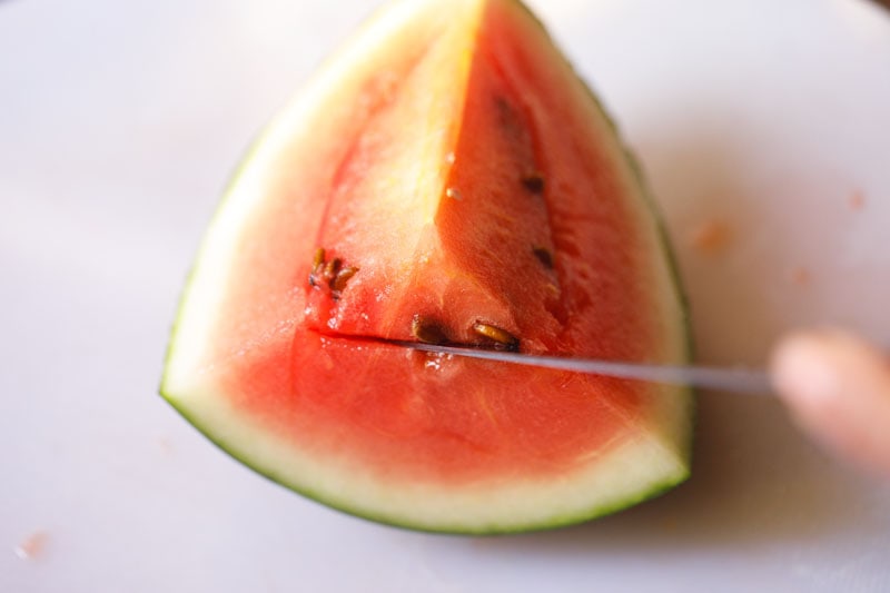 knife sliding under seed line of watermelon on short side