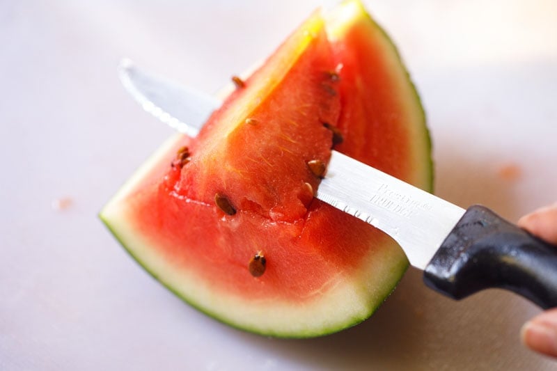 completing the cut to remove the seeded piece of watermelon