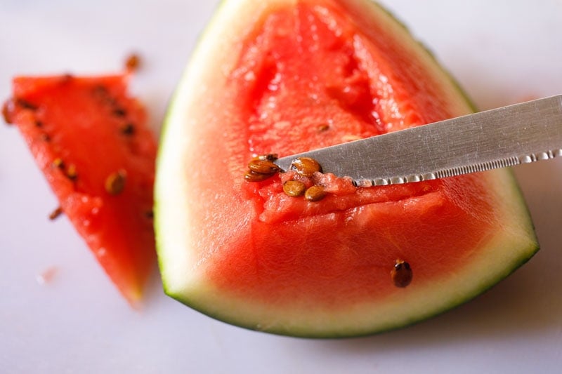 using knife to scrape seeds off larger piece of watermelon