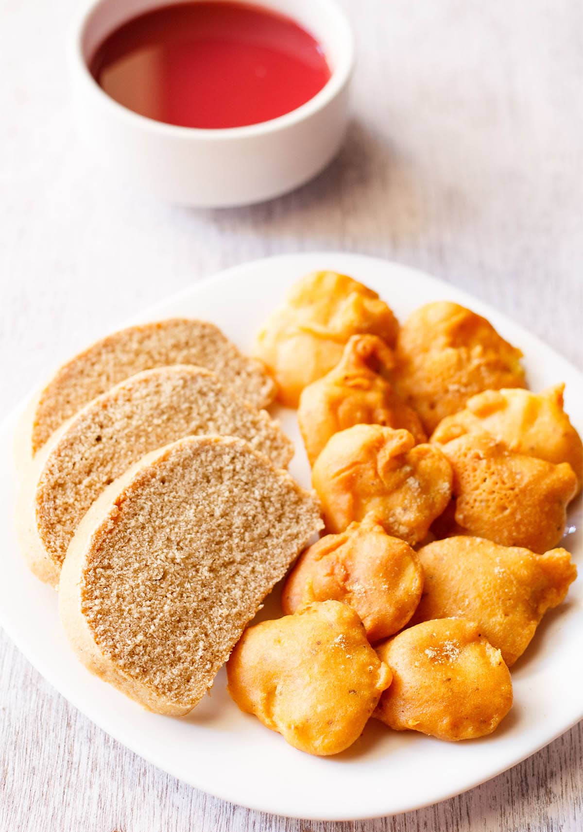 closeup shot of aloo pakora arranged on a plate with slices of wheat bread on a square white plate