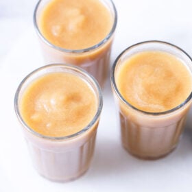 three clear glasses filled with homemade apple juice on a white table