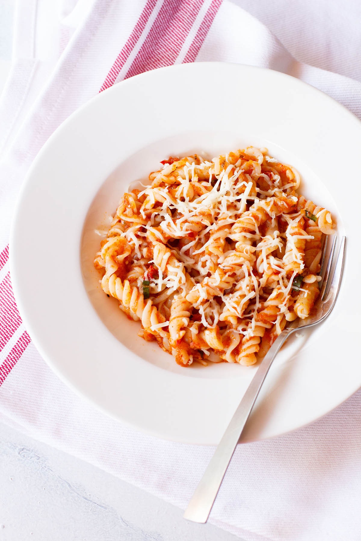 arrabiata pasta in a deep dish serving plate wit a silver fork by the side