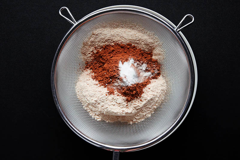 mesh sieve with flour, cocoa and other dry ingredients for making black forest cake recipe