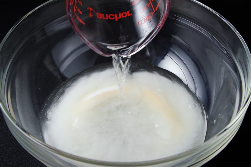 cold water being poured into a mixing bowl with sugar