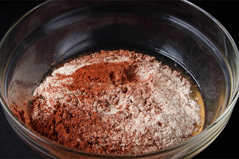 kuivia ainesosia, jotka on lisätty kulhoon märillä ainesosilla munattoman mustametsäkakun valmistamiseksi 