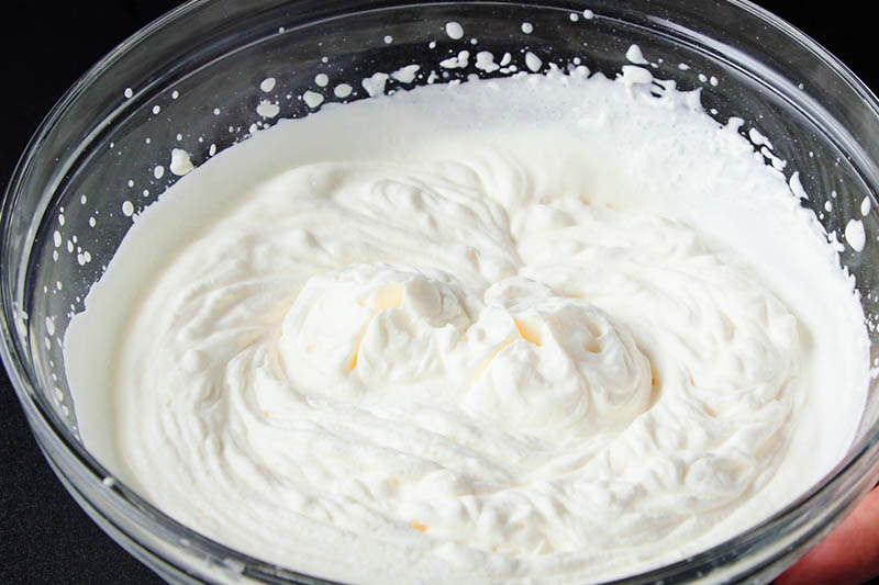 finished bowl of cream whipped to stiff peaks for frosting black forest cake