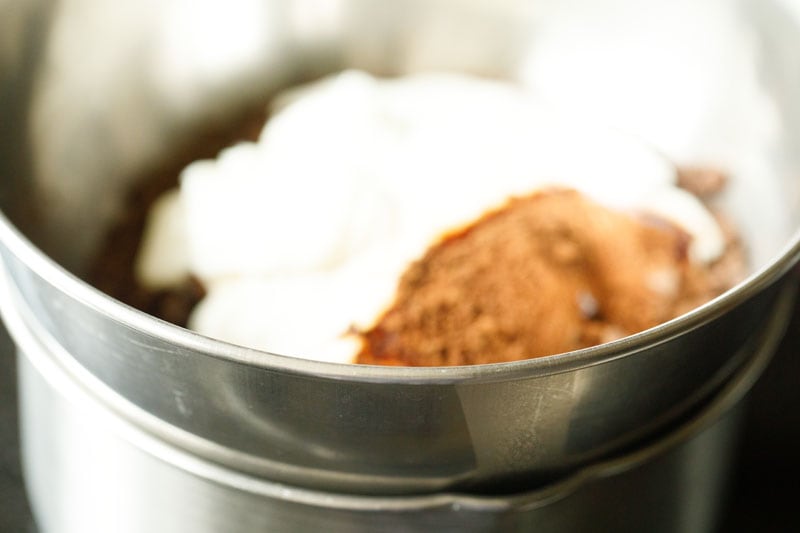 bowl with chocolate, butter, coffee, cream kept on top of saucepan