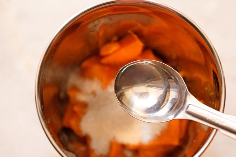 rose water being added into blender with a measuring steel spoon