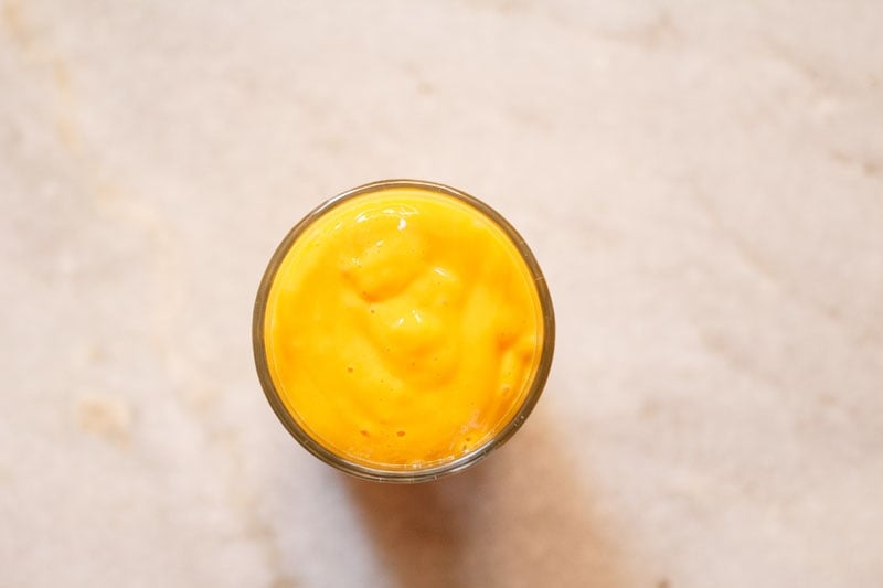 top shot of a glass filled with mango lassi