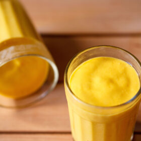 mango mousse in two glasses on a dark beige wooden board