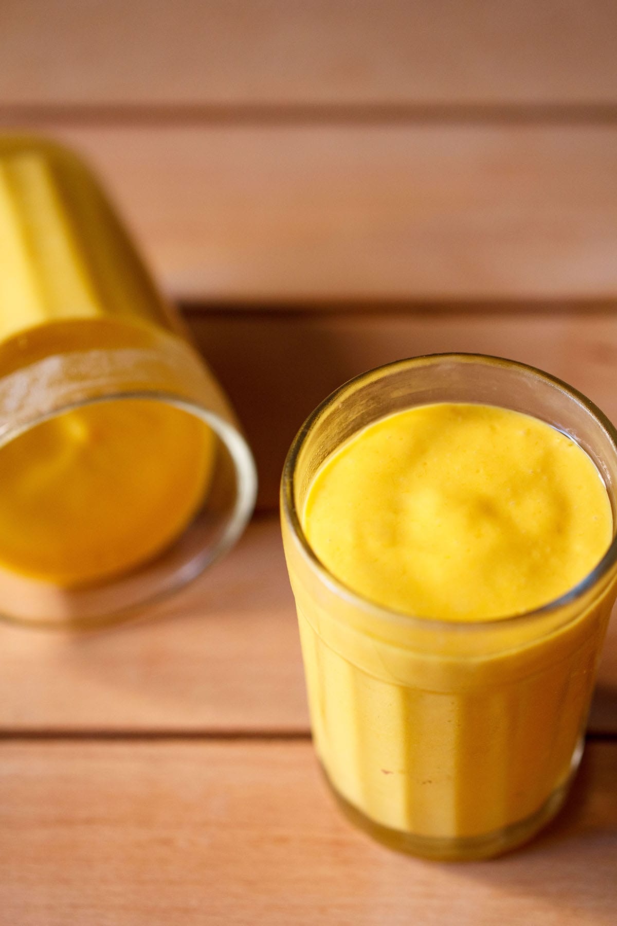 mango mousse in two glasses on a dark beige wooden board