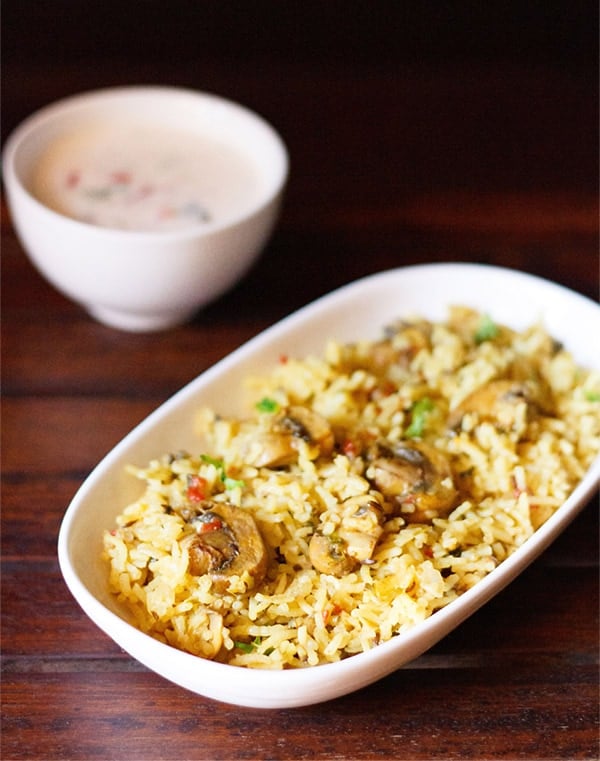 mushroom biryani in an oblong white tray on a wooden board