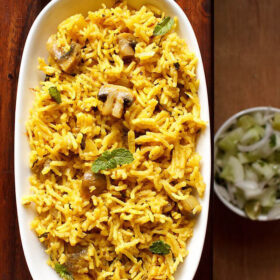 overhead shot of mushroom biryani in an oblong white tray on a wooden board