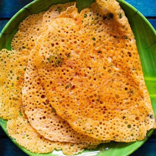 top shot of lacy crispy stack of folded oats dosa on a green plate