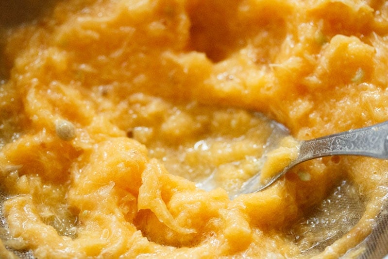 straining orange juice in a mesh strainer using spoon