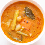 overshot shot of sambar filled in a white bowl placed on white plate