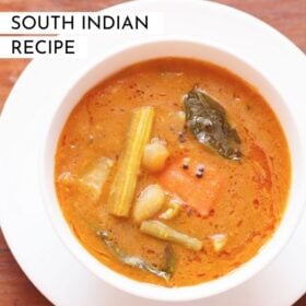 overhead shot of sambar filled in a white bowl placed on white plate on a brown wooden board with text layovers