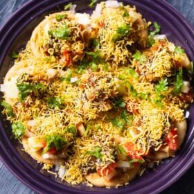 overhead shot of sev puri on a dark purple plate on a a dark blue table